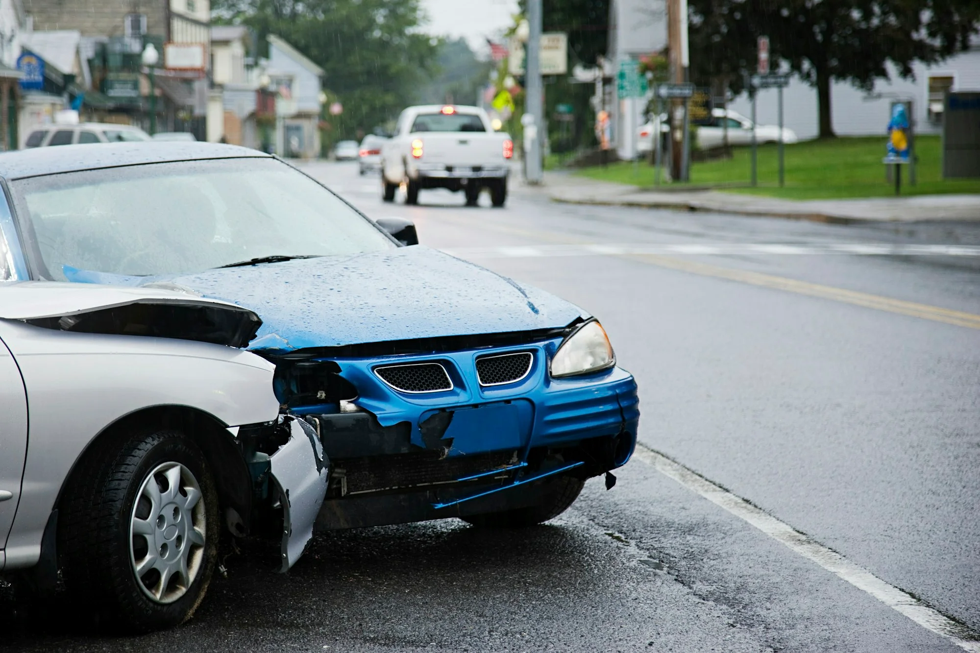 A damaged car after an accident on a wet urban road.