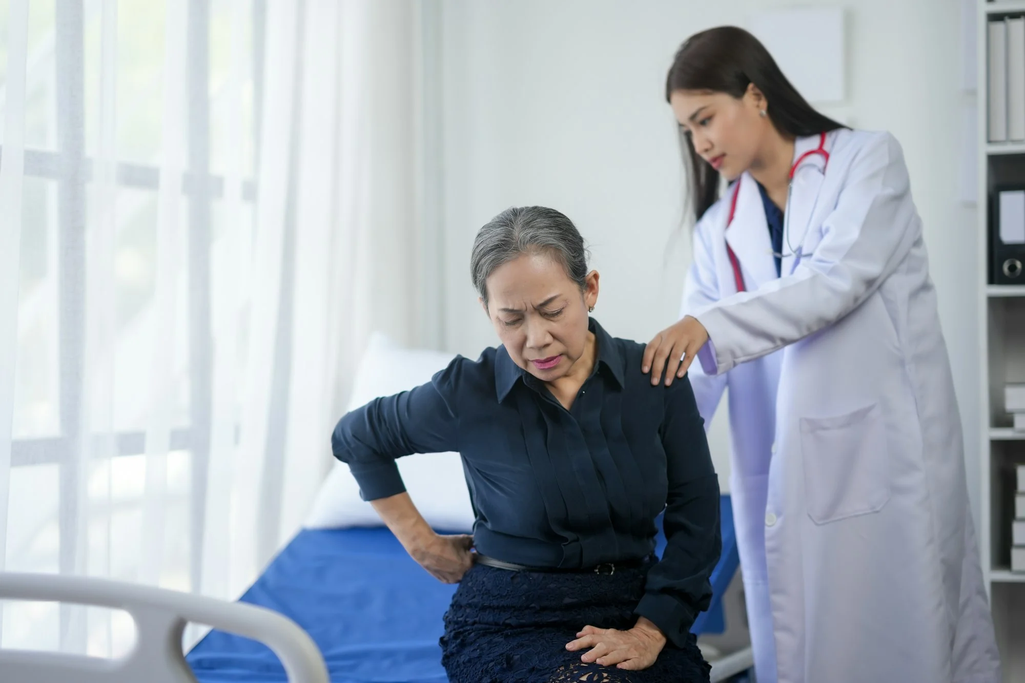 Doctor examining a senior woman with back pain in a medical office