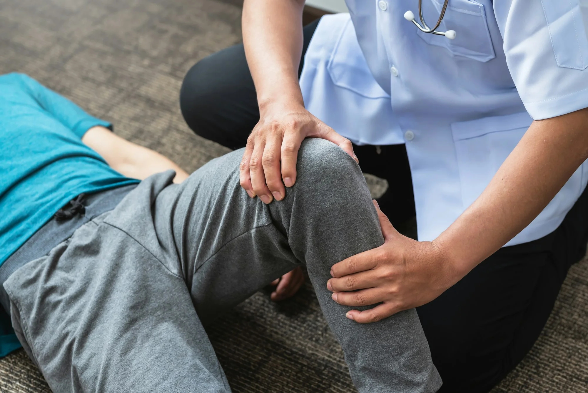 Professional orthopedic surgeon is examining a patient knee at the clinic.